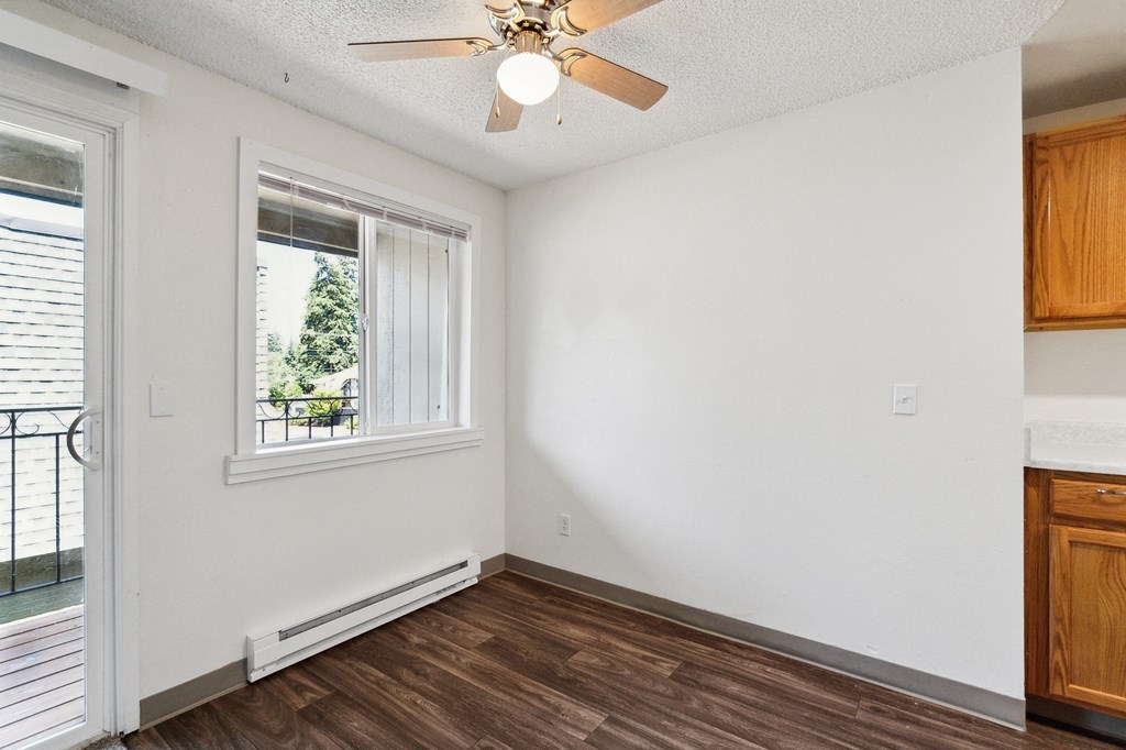 an empty living room with a ceiling fan and a window