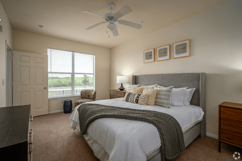 a bedroom with a large window and a ceiling fan