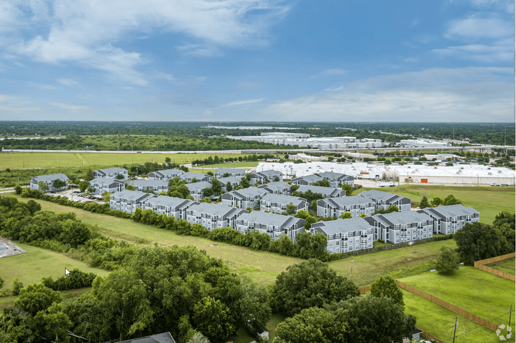 an aerial view of a row of white condominiums in a green field