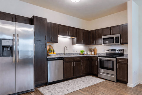 A kitchen with a refrigerator, oven, and microwave.