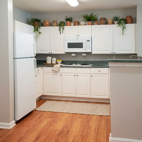 A kitchen with white cabinets and a white refrigerator.