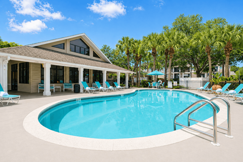 A swimming pool with a metal railing and a house with a brown roof.