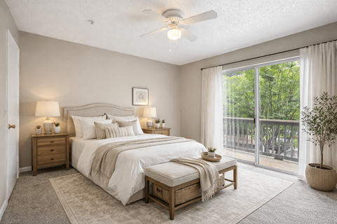 A bedroom with a large bed and a balcony overlooking trees.