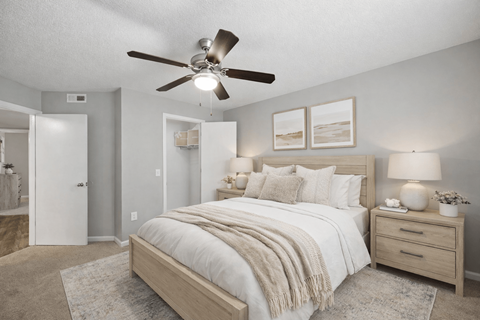 A bedroom with a bed, nightstand, and a ceiling fan.