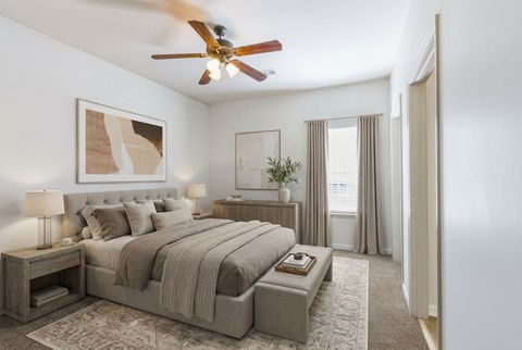 A bedroom with a large bed and a ceiling fan.