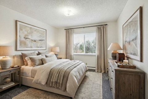 A well-lit bedroom with a large bed and a window with curtains.