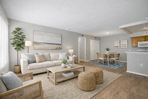 A living room with a white couch, a wooden coffee table, and a painting on the wall.