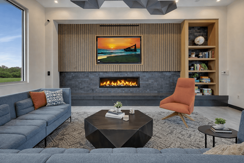 A modern living room with a fireplace and a painting of a sunset.
