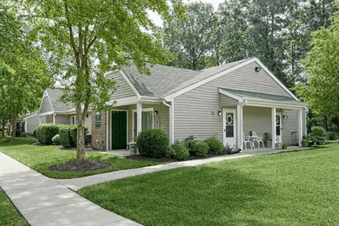 A house with a green lawn and a tree in front.
