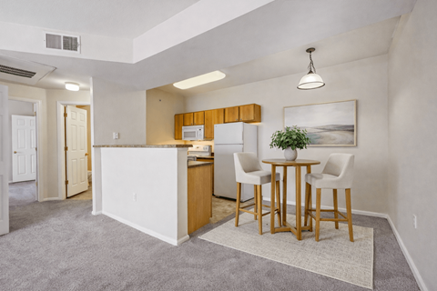 A kitchen with white cabinets and a dining table with chairs.