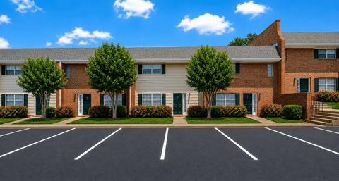 A parking lot in front of a brick building with trees.