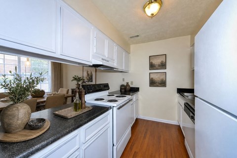 A kitchen with white cabinets and a black countertop.