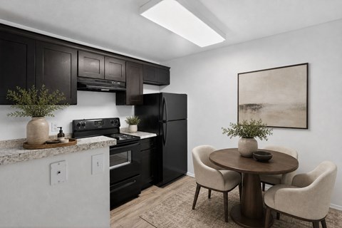A modern kitchen with black cabinets and a round table with chairs.