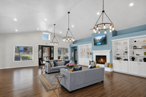 A living room with a grey couch and a fireplace.