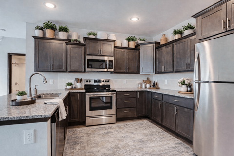 A kitchen with dark brown cabinets and a stainless steel refrigerator.