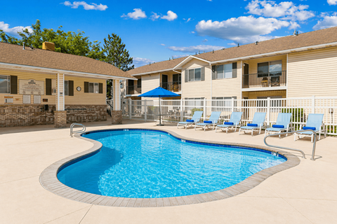 A swimming pool in a residential area with a blue umbrella.