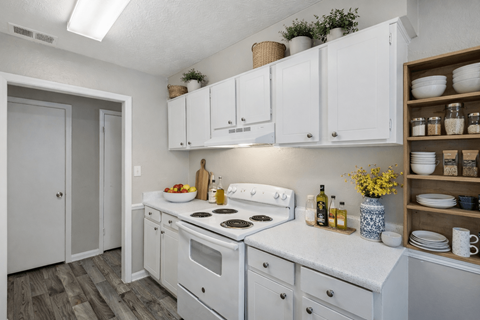 A kitchen with white cabinets and a white stove top oven.