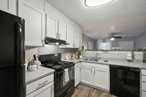A black stove top oven sits in a kitchen with white cabinets.