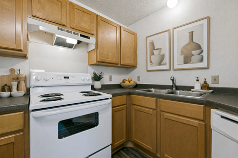 A kitchen with a white stove and wooden cabinets.