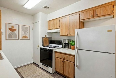A kitchen with a white refrigerator, wooden cabinets, and a stove top oven.