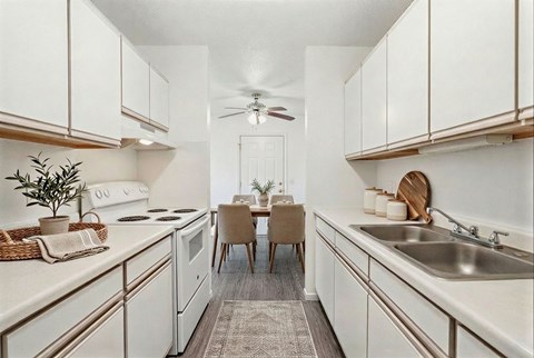 A kitchen with white cabinets and a dining table with chairs.
