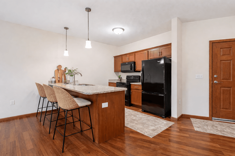 A kitchen with a black refrigerator and wooden floors.
