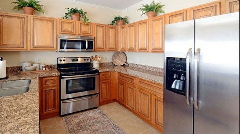 A kitchen with wooden cabinets and a stainless steel refrigerator.
