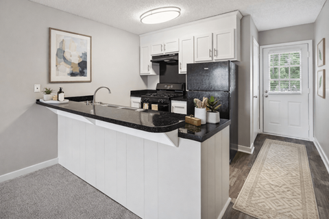 A kitchen with a black fridge and stove top oven.