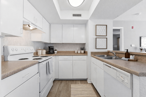 A kitchen with white cabinets and a beige countertop.