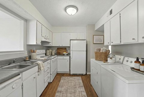 A white kitchen with a refrigerator, sink, and oven.