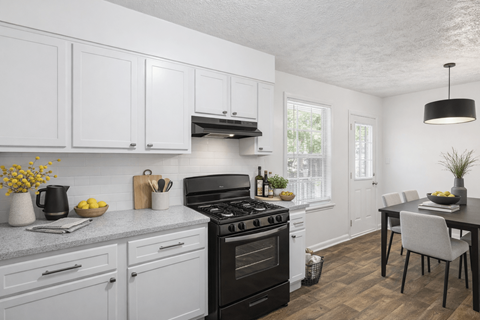 A kitchen with white cabinets and a black stove top.