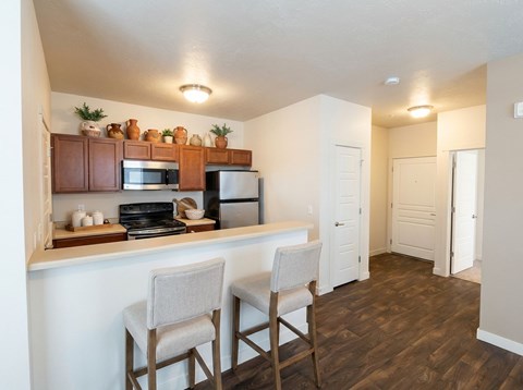 A kitchen with a white counter top and two chairs.