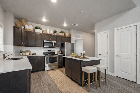 A modern kitchen with dark wood cabinets and stainless steel appliances.