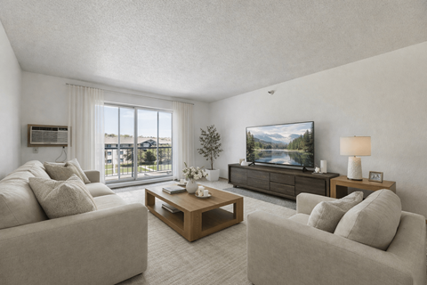 A living room with a grey couch, a wooden coffee table, and a television on a cabinet.