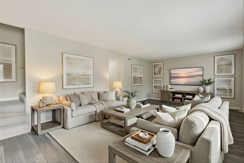 A well-lit living room with a grey sofa, a coffee table, and a painting on the wall.