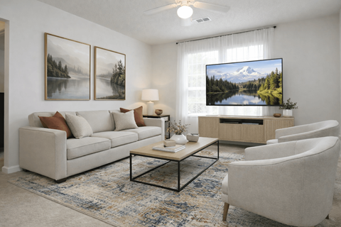 A living room with a couch, a chair, a coffee table, and a television displaying a mountain landscape.