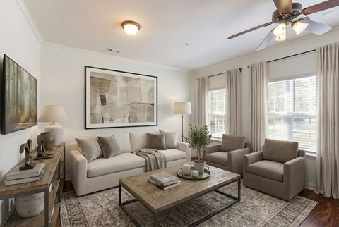 A living room with a couch, chairs, a coffee table, and a ceiling fan.
