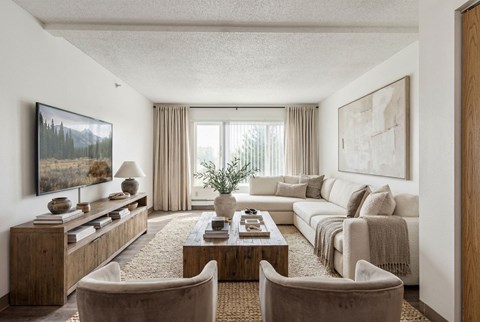 A living room with a large couch, a coffee table, and a painting on the wall.