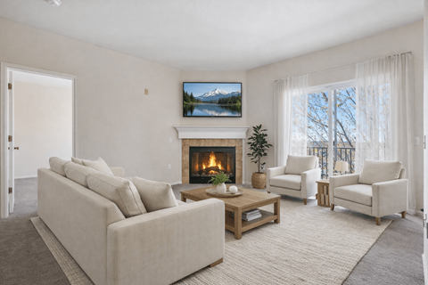 A living room with a fireplace and a painting of a mountain landscape on the wall.