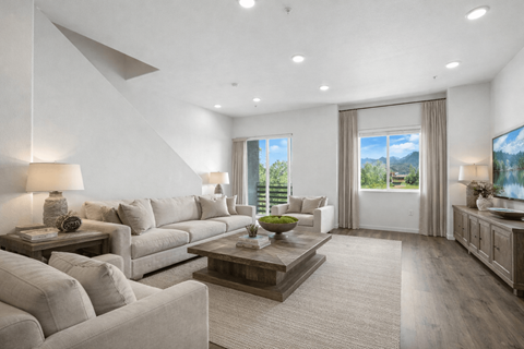 A well-lit, modern living room with a large window and a flat-screen TV.