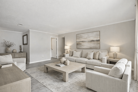 A living room with a grey couch, a coffee table, and a painting on the wall.