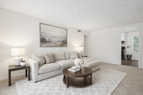 A living room with a white couch and a painting on the wall.