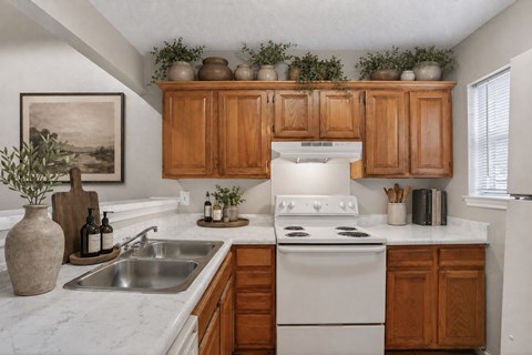 A kitchen with wooden cabinets and a white stove top oven.