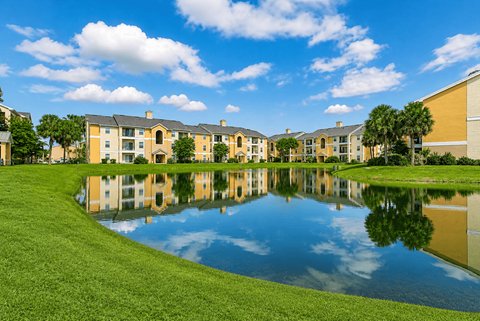 A large building complex is reflected in a pond.