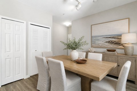 A dining room with a wooden table and white chairs.