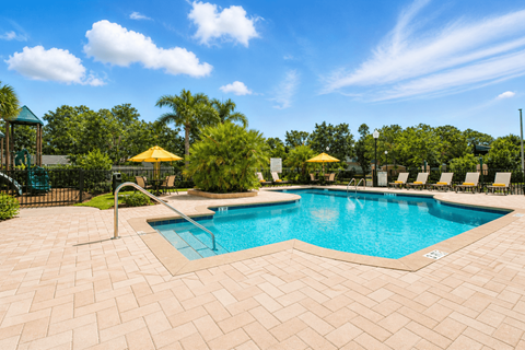 A large outdoor swimming pool surrounded by a brick patio.