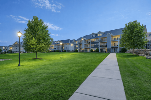 A long concrete pathway leads to a building with a grassy area on either side.
