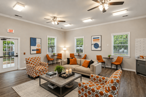 A living room with orange and white furniture and a ceiling fan.