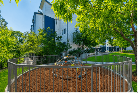 A playground with a swing set in front of a building.