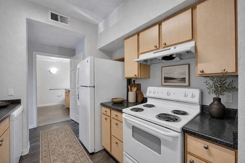 A kitchen with a white stove and wooden cabinets.